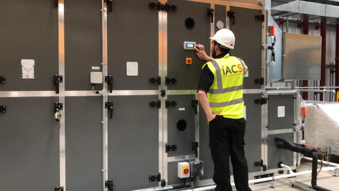 An iACS engineer optimising the energy efficiency of a large commercial HVAC system by adjusting its digital control panel.